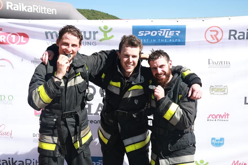Squadra dei vigili del fuoco al traguardo davanti alla parete sponsor
